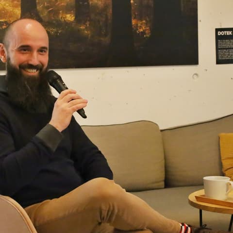 Beseda s Pavlem Polou: host s mikrofonem se usmívá na pohovce