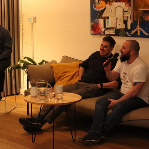 Beseda s Pastoral Brothers: moderátor a dva hosté na pohovce, jeden mluví do mikrofonu