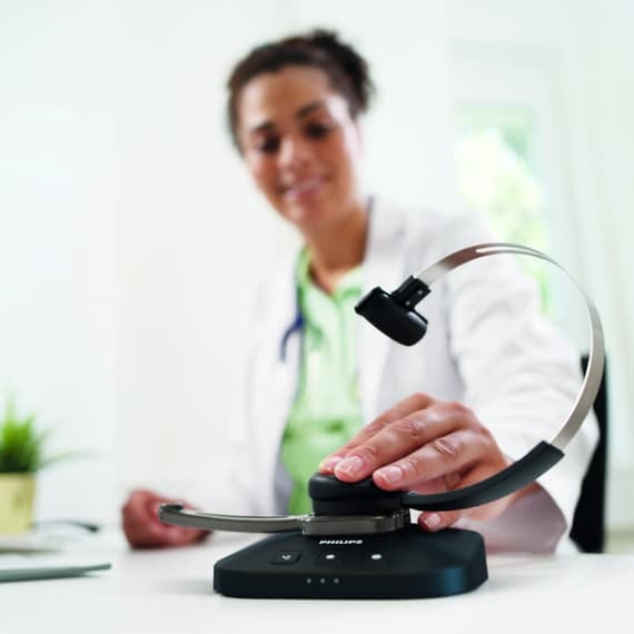 Lékařka odkládá náhlavní soupravu Philips do nabíjecí stanice