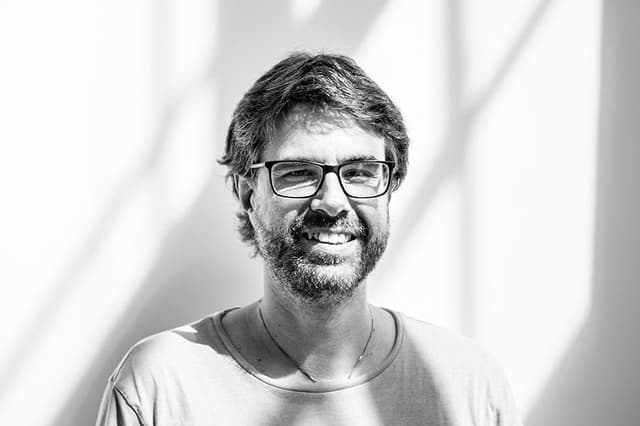 Petr Třešňák, novinář týdeníku Respekt, s úsměvem na světlé zdi se stíny oken