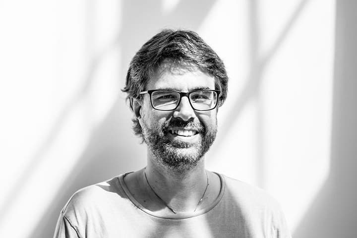 Petr Třešňák, novinář týdeníku Respekt, s úsměvem na světlé zdi se stíny oken