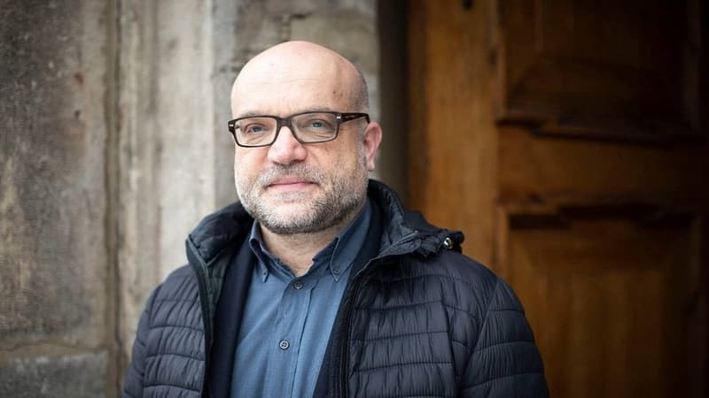 Tomáš Petráček v bundě před dřevěnými dveřmi